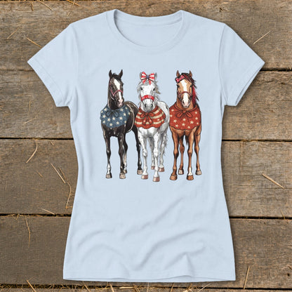 Three horses in festive patriotic attire stand together, with patriotic bows and star-patterned coverings.