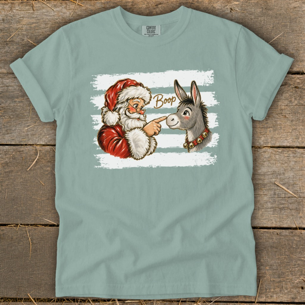 Santa touching a donkey's nose with the word "Boop" on a shirt.