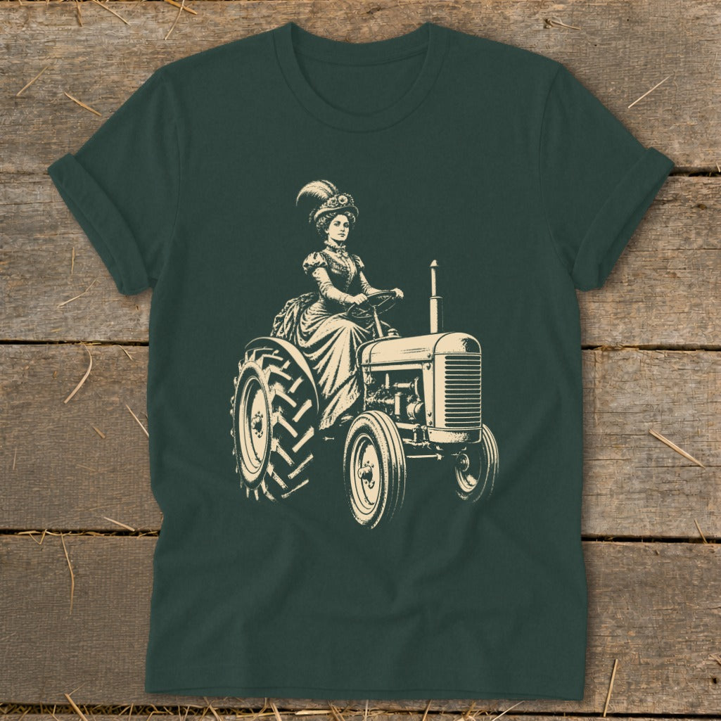 Woman in vintage dress driving a tractor, cream graphic on dark green t-shirt.