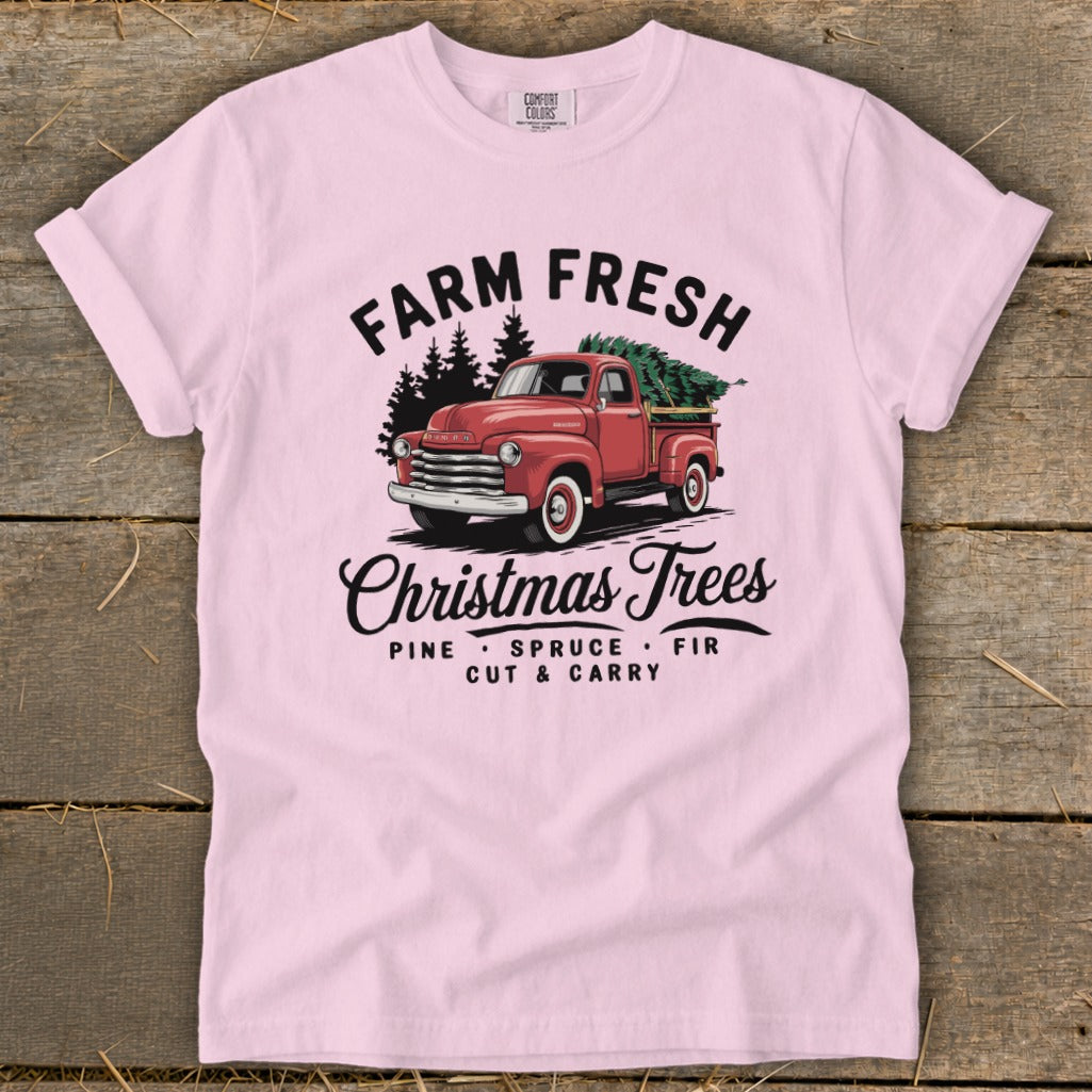 Pink t-shirt with red truck carrying Christmas trees and text "Farm Fresh Christmas Trees".