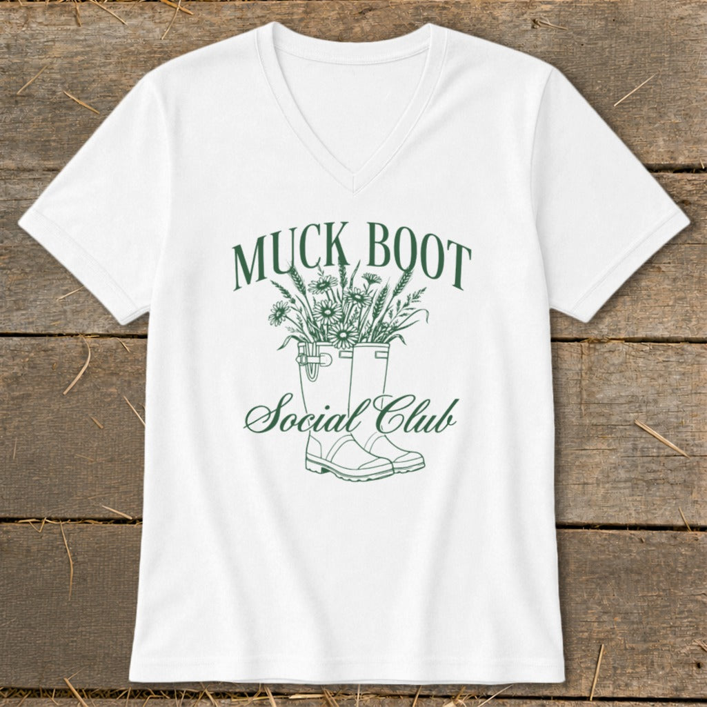 White t-shirt with green text "MUCK BOOT Social Club" and illustration of boots with flowers.