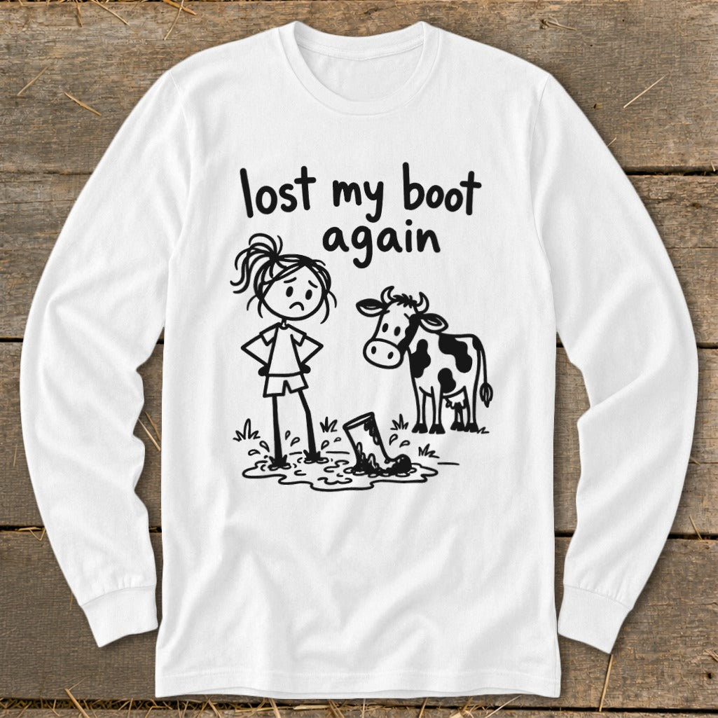 White long-sleeve t-shirt with a black graphic of a girl and cow standing by a muddy boot and text reading "lost my boot again."