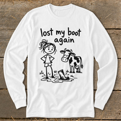 White long-sleeve t-shirt with a black graphic of a girl and cow standing by a muddy boot and text reading "lost my boot again."