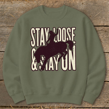 Green sweatshirt with a distressed graphic of a bronc rider and text "Stay Loose & Stay On."