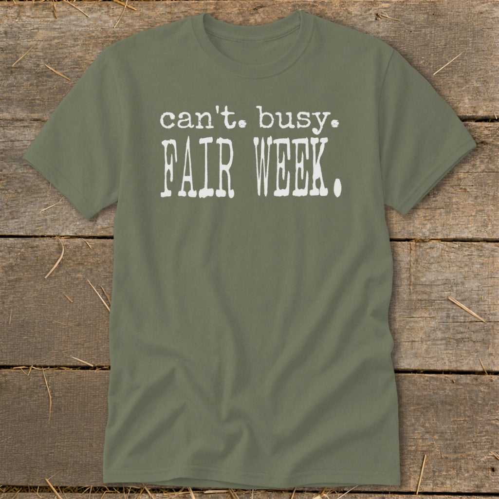 Olive green t-shirt with white text "can't. busy. FAIR WEEK."