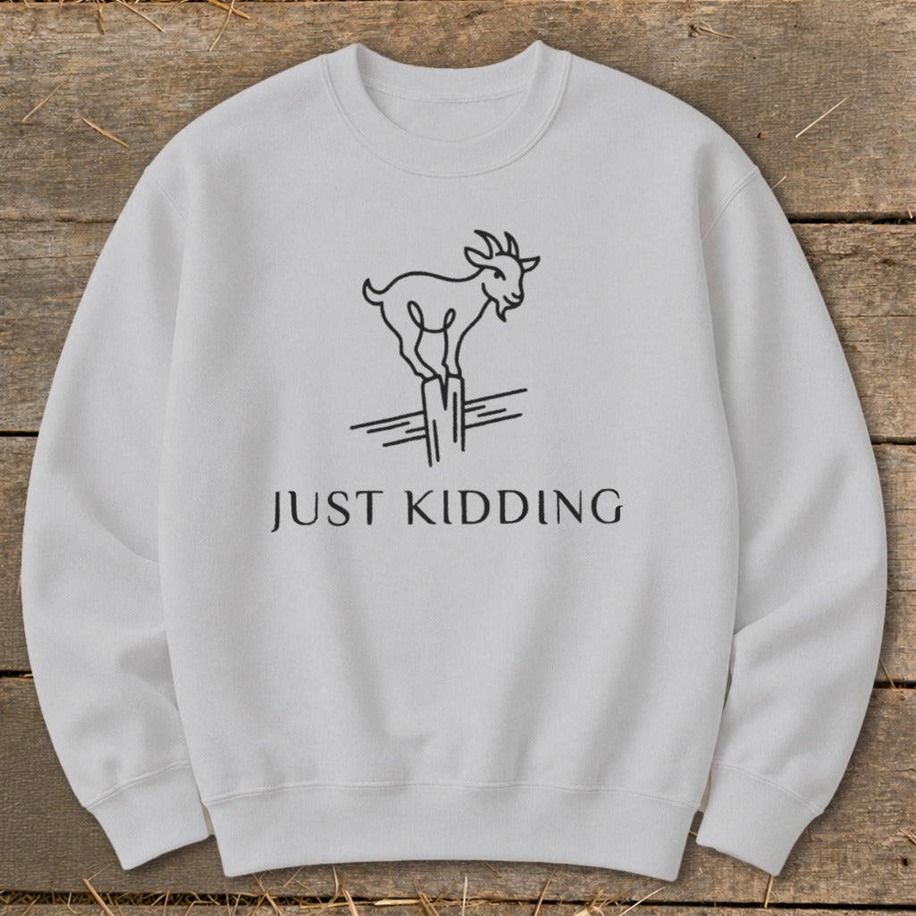 Light grey sweatshirt with a black line drawing of a goat on a fence post and text reading "JUST KIDDING".