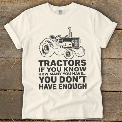White t-shirt with a tractor graphic and text: "Tractors if you know how many you have... you don't have enough."