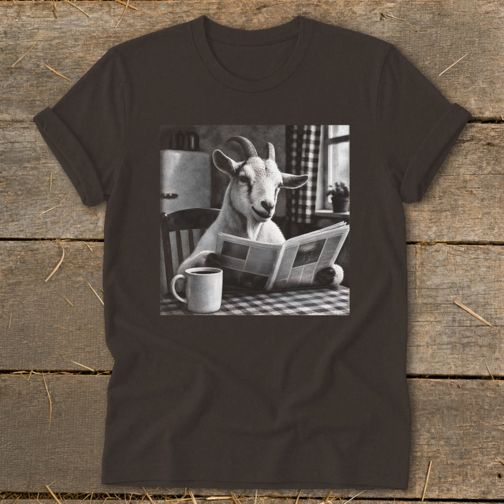 A dark brown t-shirt featuring a graphic of a goat sitting at a table reading a newspaper beside a coffee mug.