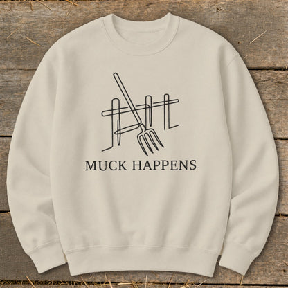 Light beige sweatshirt with a minimalist line drawing of a pitchfork and fence, and text "MUCK HAPPENS".