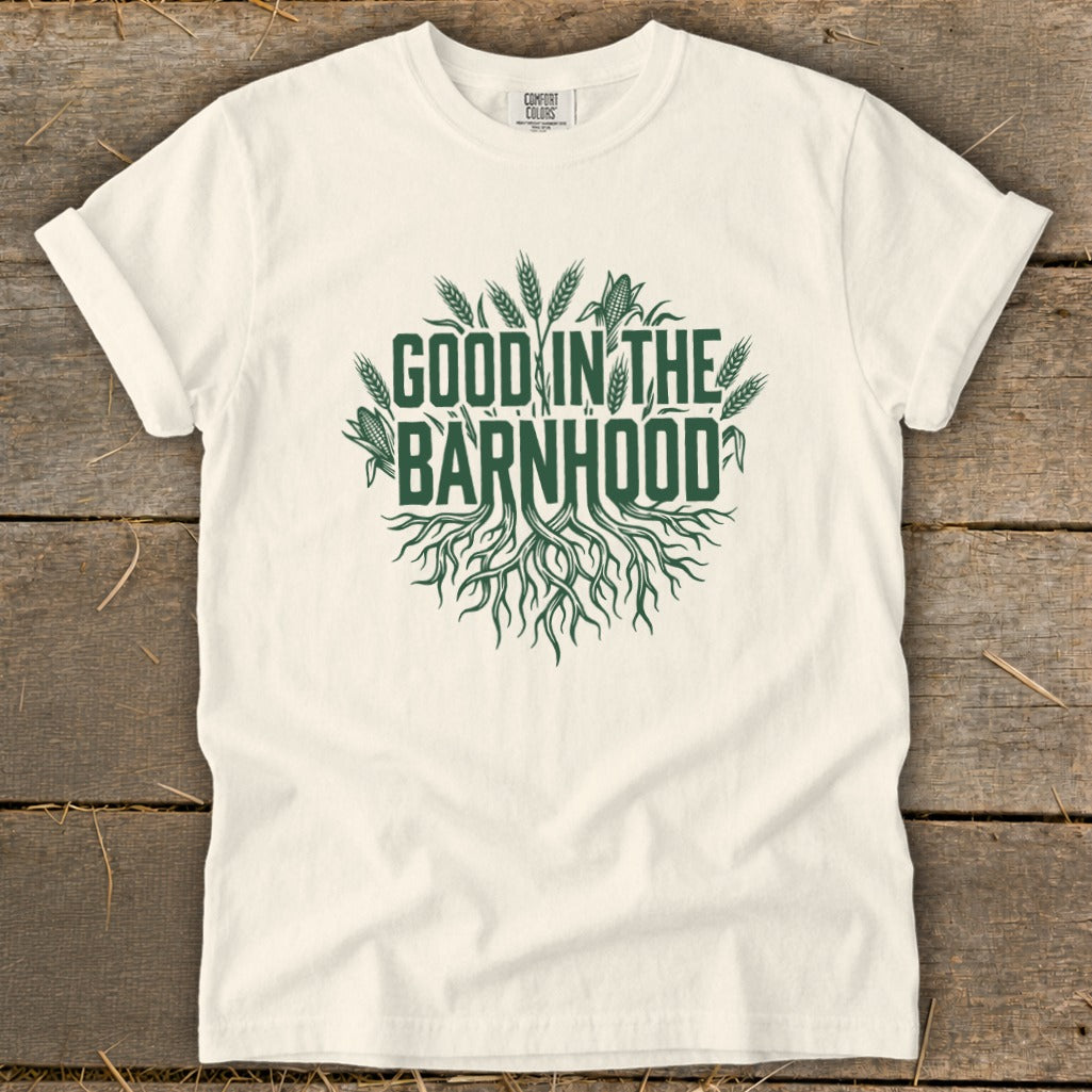 White t-shirt with green text and graphics reading "GOOD IN THE BARNHHOOD" with roots and crops.