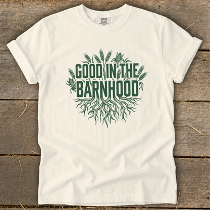 White t-shirt with green text and graphics reading "GOOD IN THE BARNHHOOD" with roots and crops.