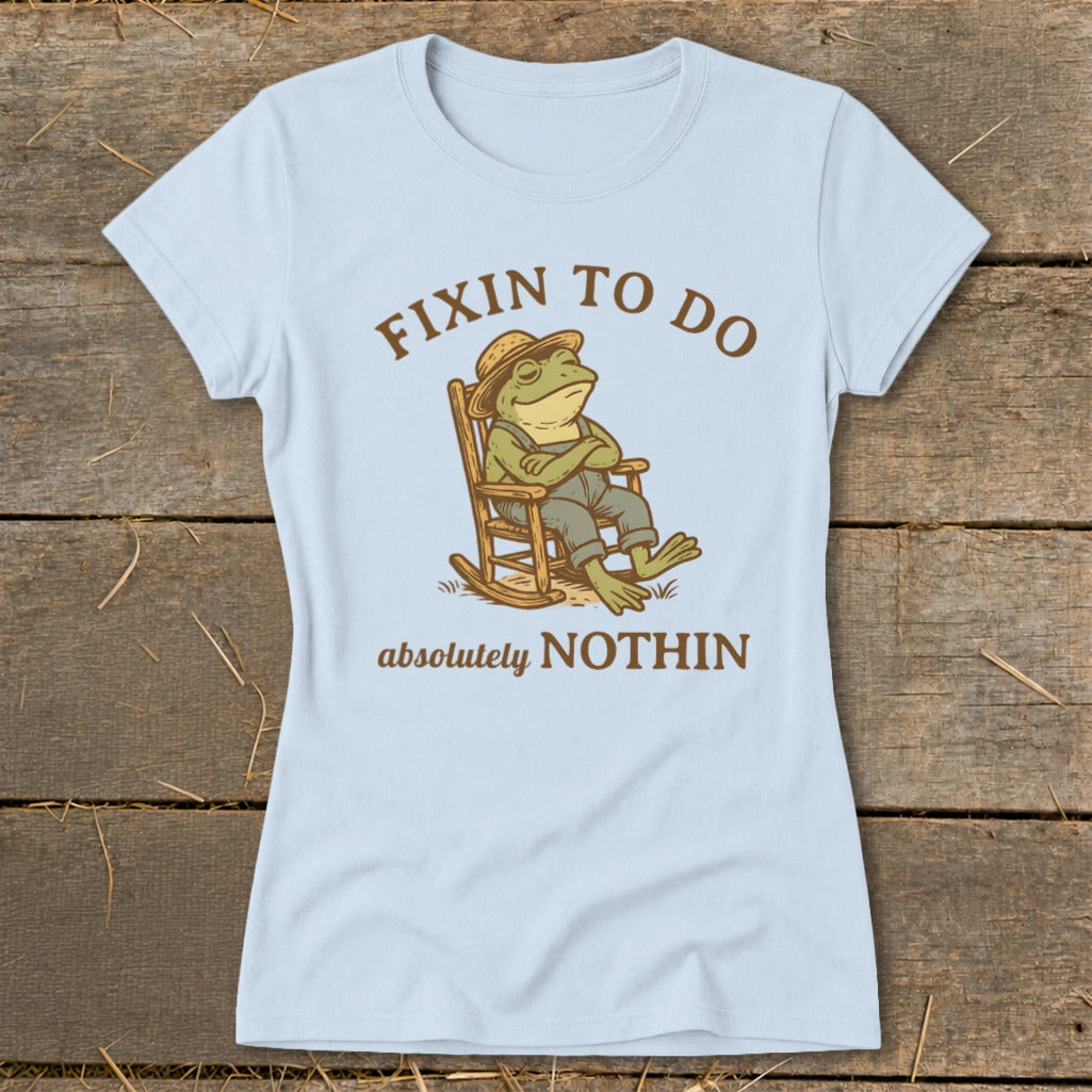 Light blue t-shirt with graphic of frog in rocking chair, text "Fixin to Do Absolutely Nothin".