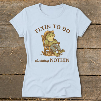 Light blue t-shirt with graphic of frog in rocking chair, text "Fixin to Do Absolutely Nothin".