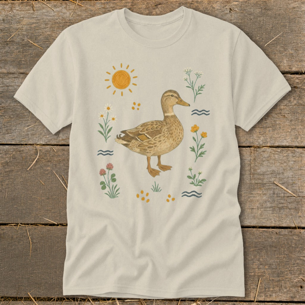 T-shirt with a brown duck surrounded by flowers, sun, and water.