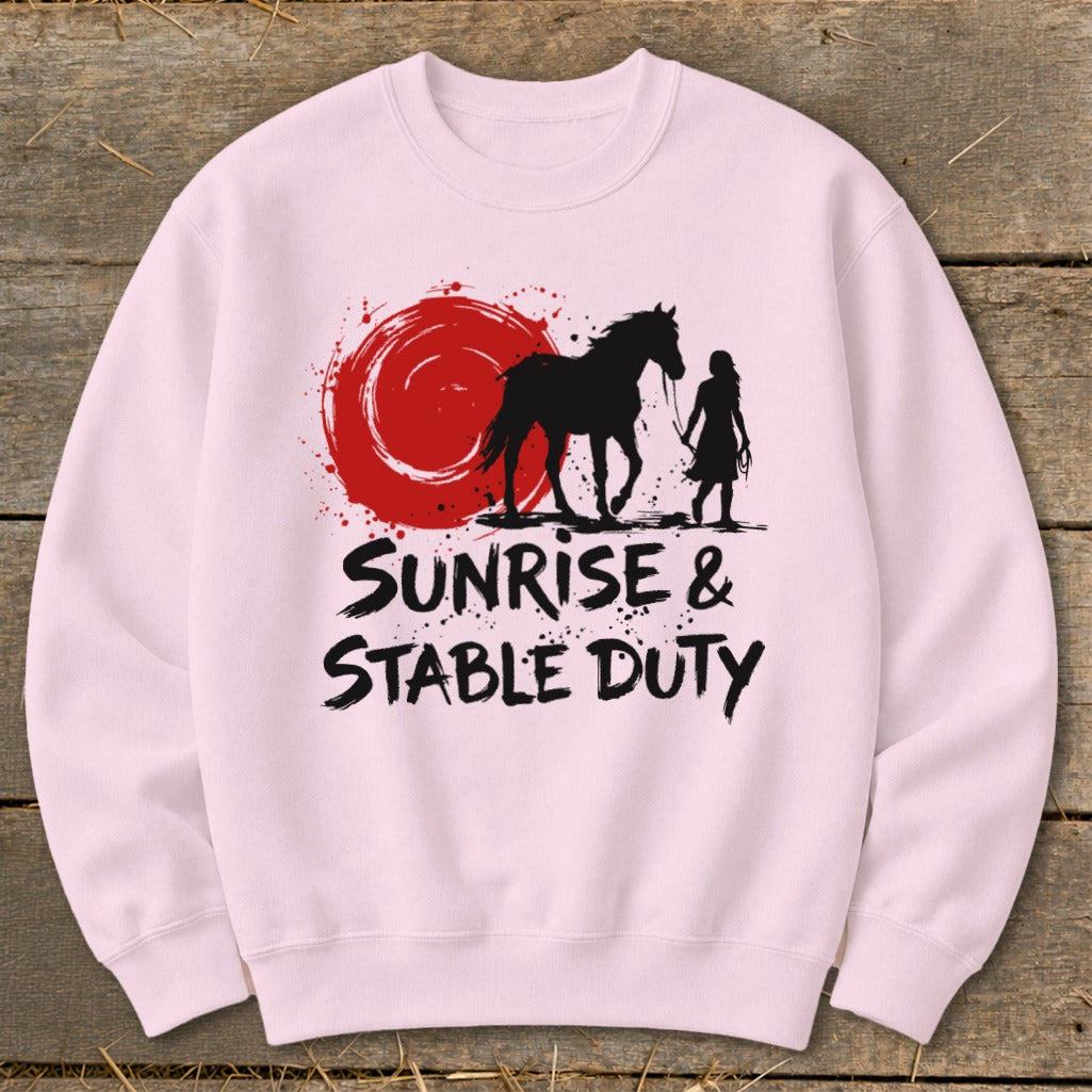 Pink sweatshirt with silhouette of horse and rider under a red sun, text "Sunrise & Stable Duty."