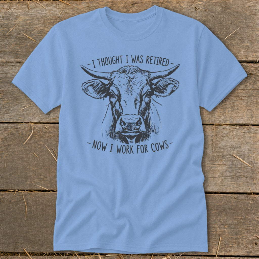 Light blue t-shirt with sketch of a cow and text "I thought I was retired - Now I work for cows".