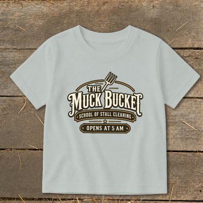 Light blue t-shirt with "The Muck Bucket School of Stall Cleaning Opens at 5 AM" graphic.