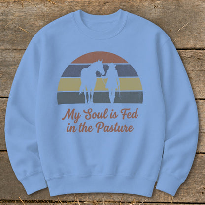 Light blue sweatshirt with horse and rider silhouette over striped sunset and text.