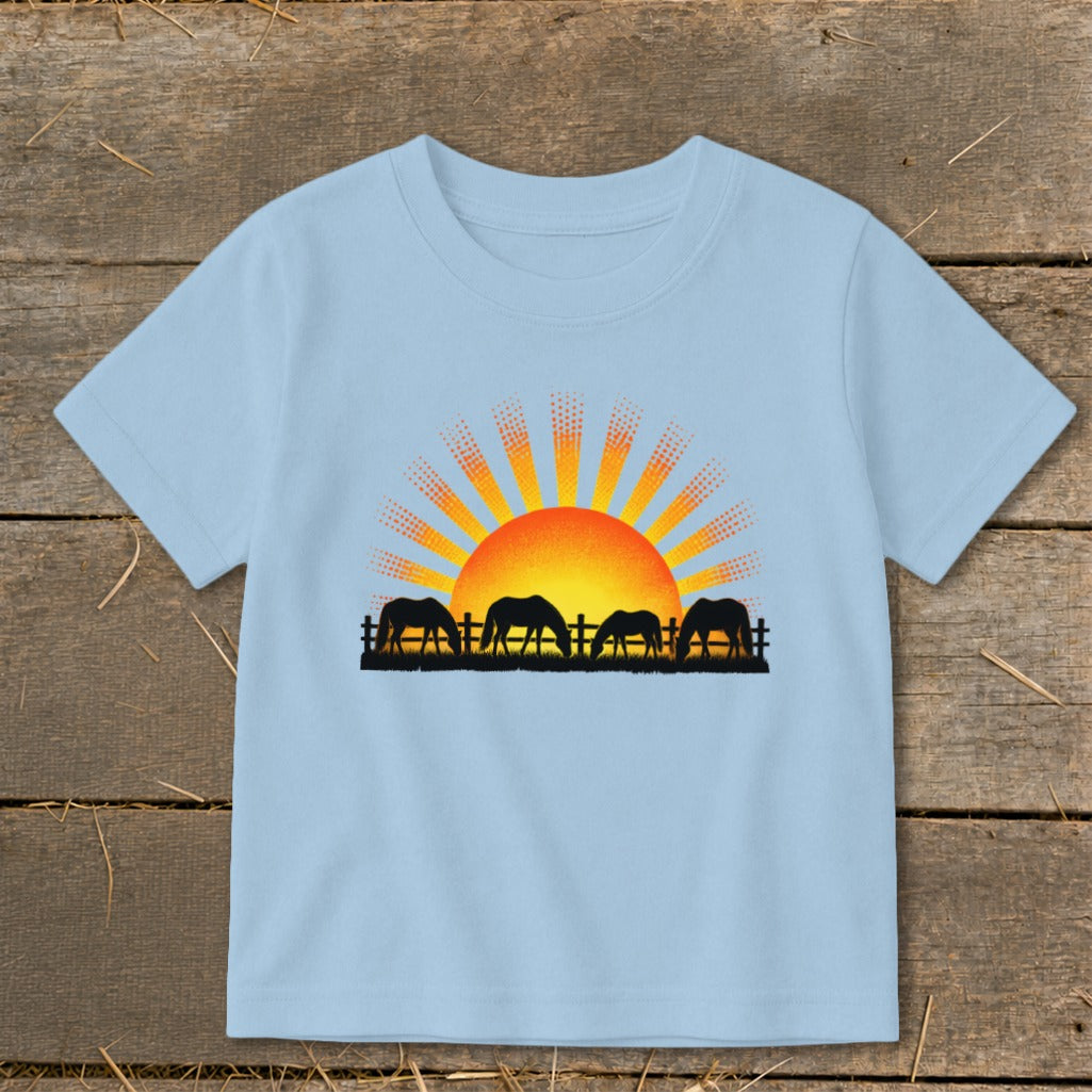 T-shirt with four horses grazing in front of a stylized sunrise graphic.