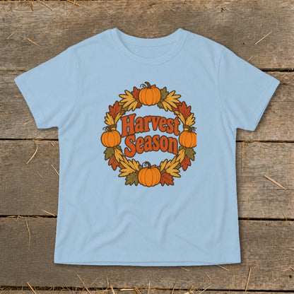 Light blue t-shirt with "Harvest Season" text inside a pumpkin and leaf wreath.