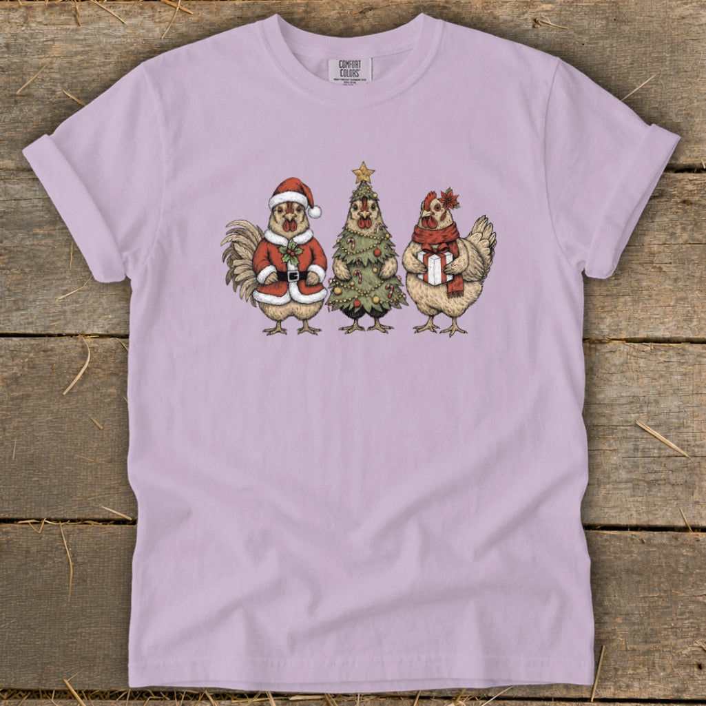 Rooster in Santa suit, chicken Christmas tree, and chicken with gift on light purple shirt.