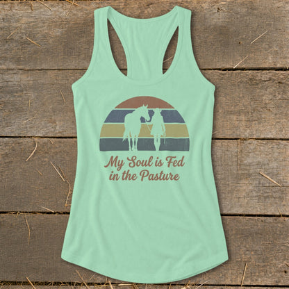 Mint green tank top with horse and rider silhouette over striped sunset and text "My Soul is Fed in the Pasture."