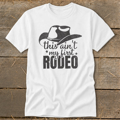 White t-shirt with a cowboy hat graphic and "this ain't my first RODEO" text.