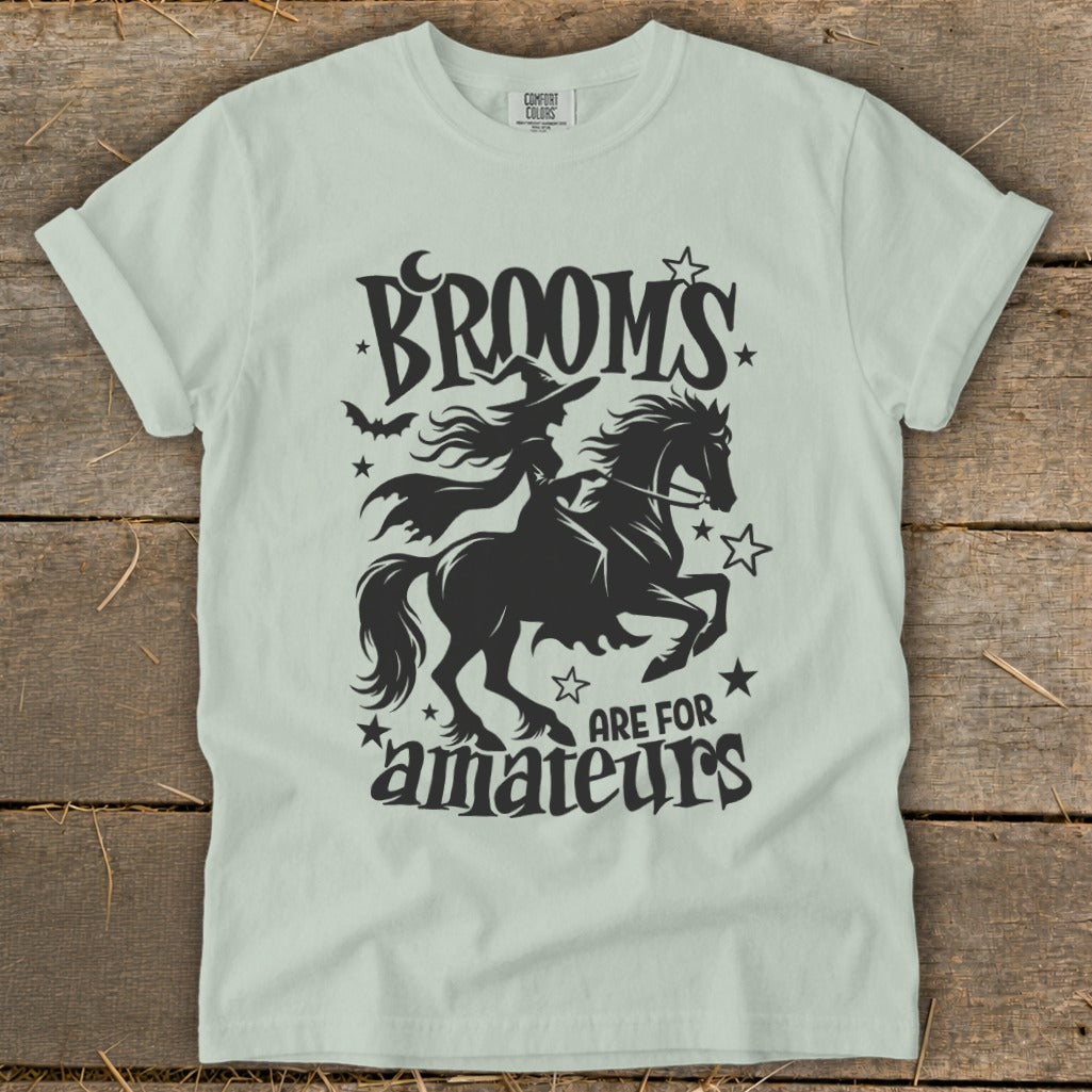 Black silhouette of a witch on a horse with text "Brooms are for amateurs".