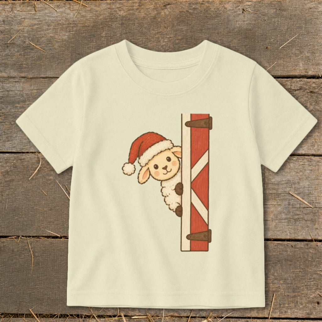 Cream t-shirt with a sheep wearing a Santa hat peeking from behind a barn door.