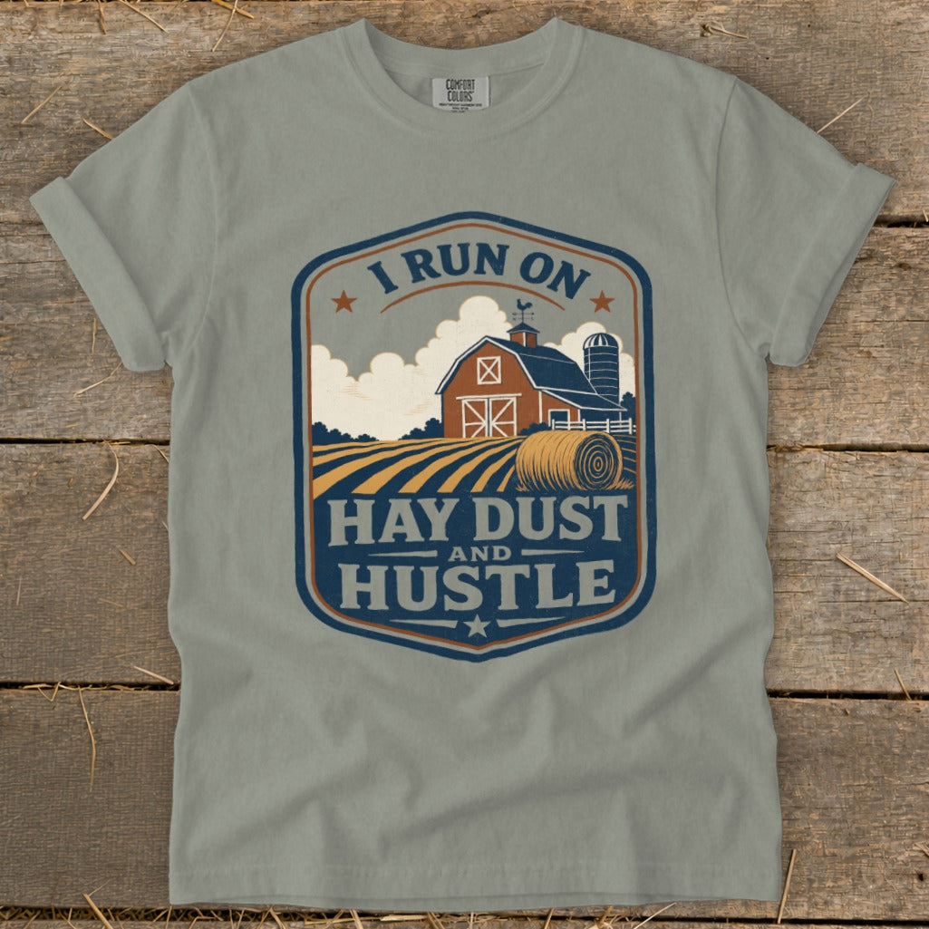 Gray t-shirt with "I RUN ON HAY DUST AND HUSTLE" graphic of a barn and hay bale.