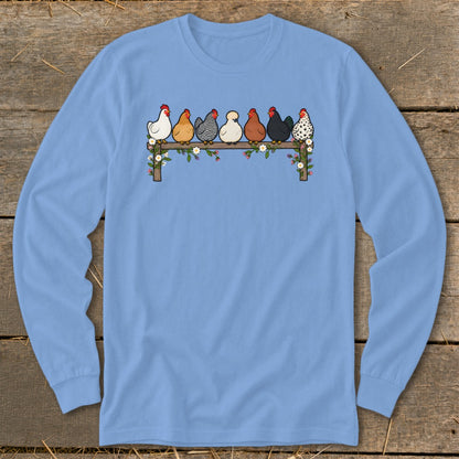 Light blue long-sleeved shirt with a graphic of seven colorful chickens sitting on a flower-adorned fence.