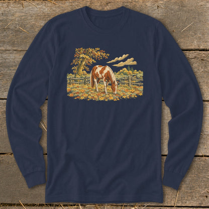 Brown and white horse grazing in autumn landscape with a wooden fence.