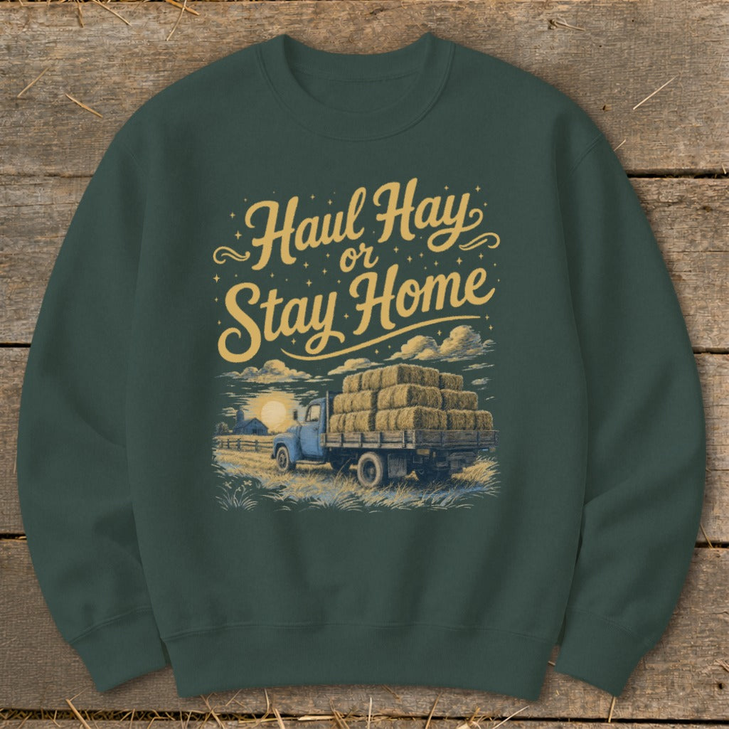 Green sweatshirt with "Haul Hay or Stay Home" text and illustration of a blue truck loaded with hay bales.