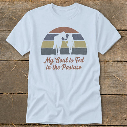 White t-shirt with retro graphic of horse and rider with text "My Soul is Fed in the Pasture".