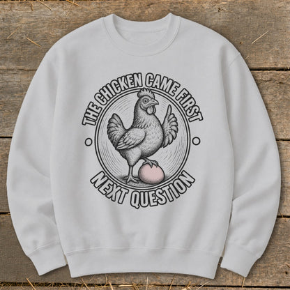 White sweatshirt with a graphic of a chicken and egg, "The Chicken Came First Next Question".