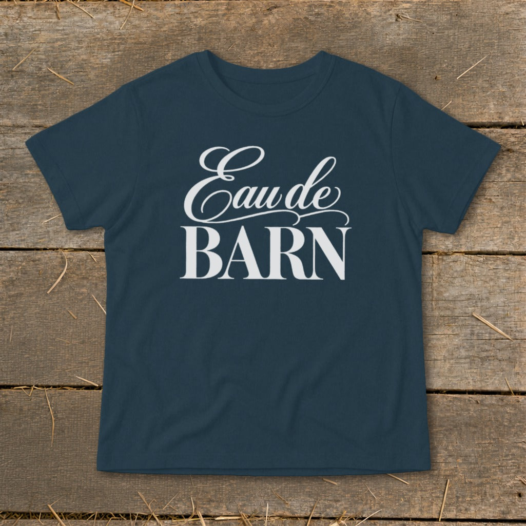 Navy t-shirt with white text "Eau de BARN" on a wooden background.