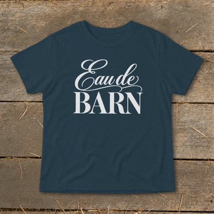 Navy t-shirt with white text "Eau de BARN" on a wooden background.