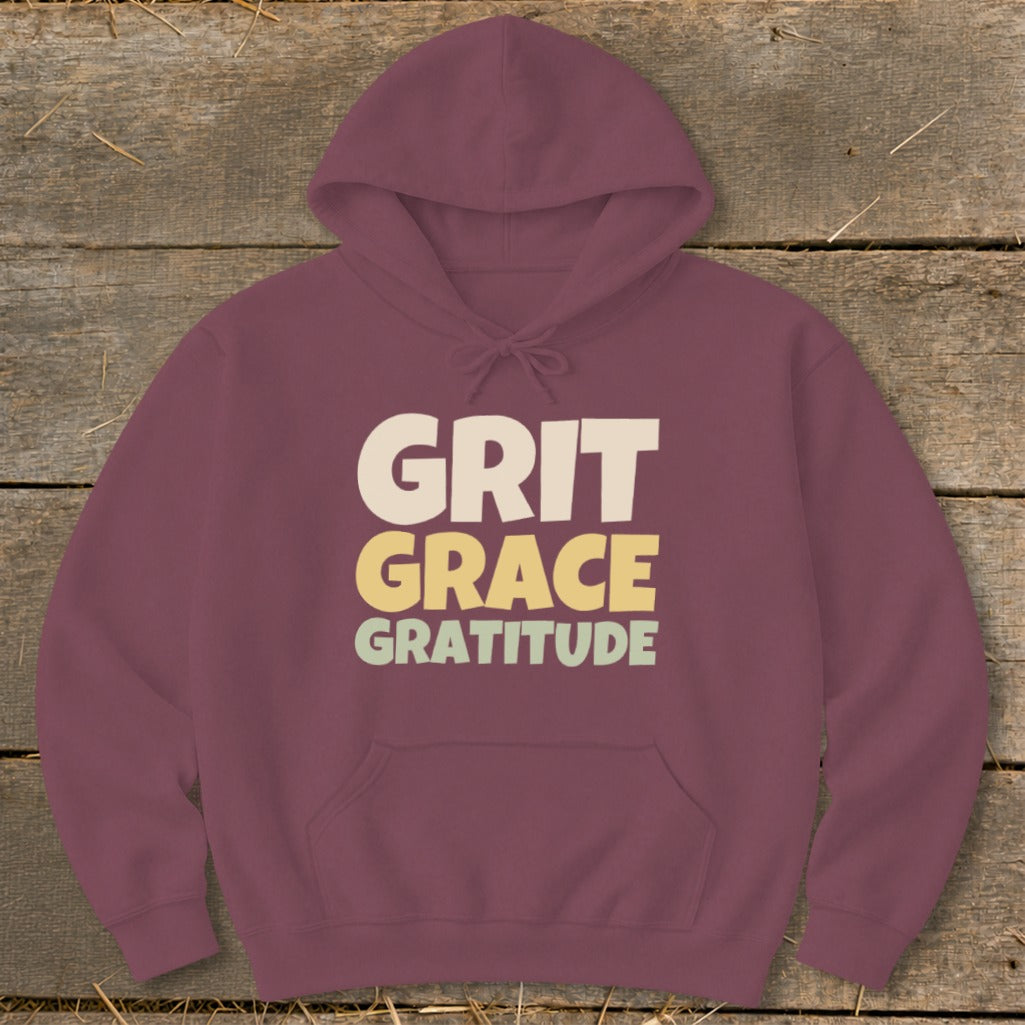 Maroon hoodie featuring stacked text in cream, yellow, and light green reading GRIT GRACE GRATITUDE.