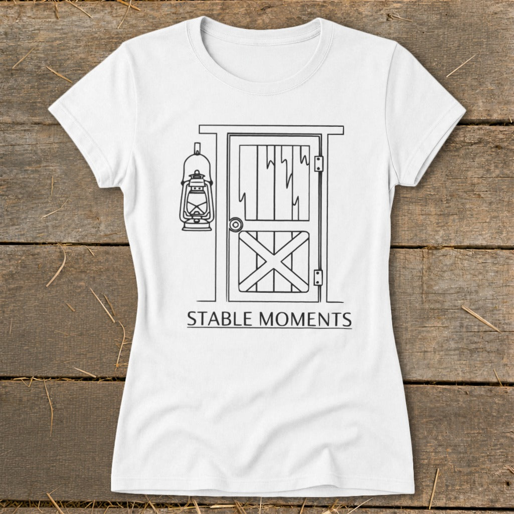 White t-shirt with a line drawing of a barn door, lantern, and text "STABLE MOMENTS".