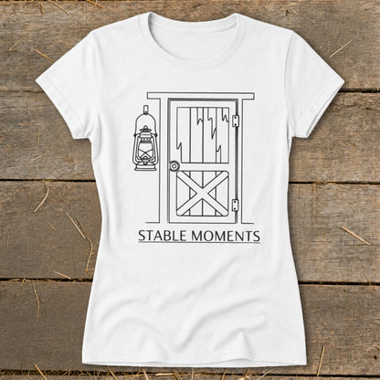 White t-shirt with a line drawing of a barn door, lantern, and text "STABLE MOMENTS".