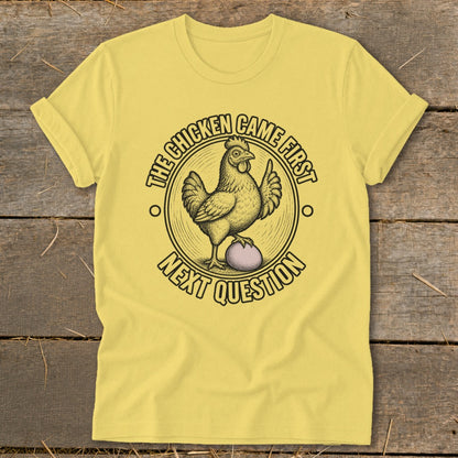 Yellow t-shirt with a chicken on an egg and text "The chicken came first, next question".