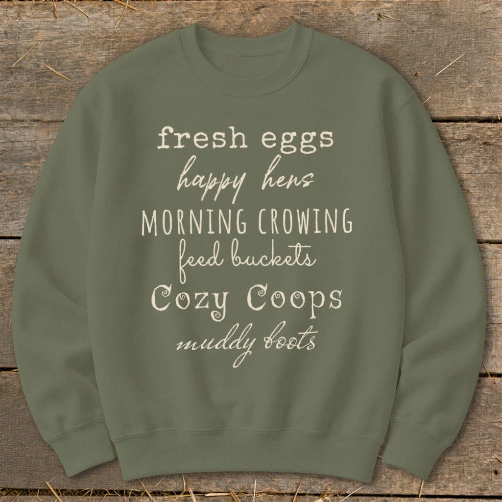Olive green sweatshirt with white text listing farm-related phrases like "fresh eggs" and "happy hens."