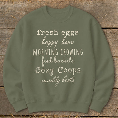 Olive green sweatshirt with white text listing farm-related phrases like "fresh eggs" and "happy hens."