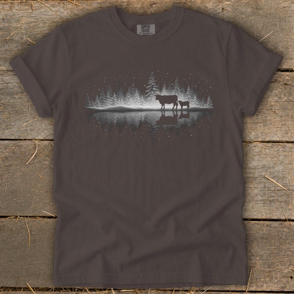Dark grey t-shirt with a white silhouette of cows near a snowy forest and water.
