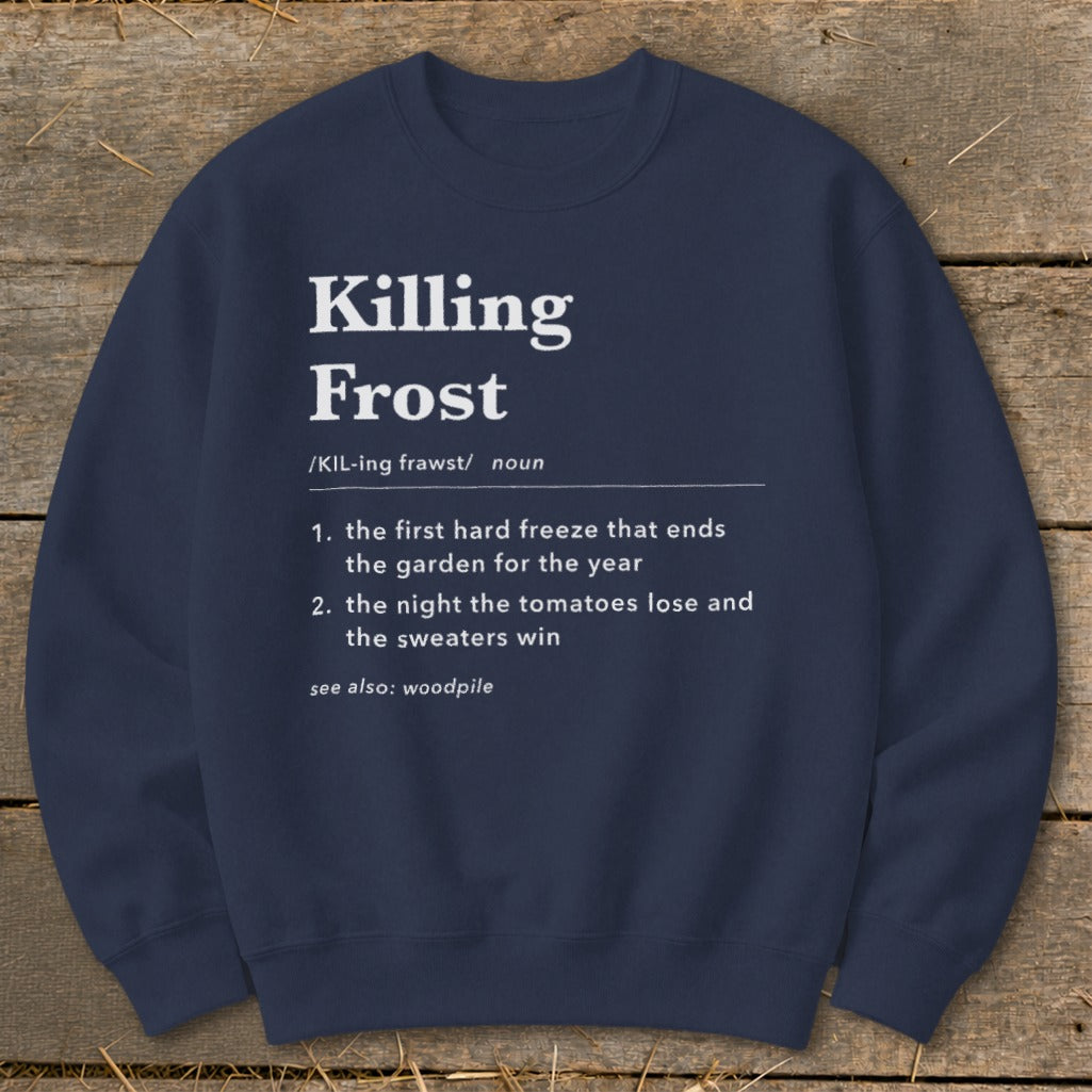 A dark blue crewneck sweatshirt with white text defining killing frost laid flat on a wooden surface.