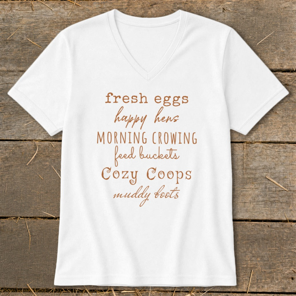 White v-neck shirt with "fresh eggs happy hens MORNING CROWING feed buckets Cozy Coops muddy boots" text.