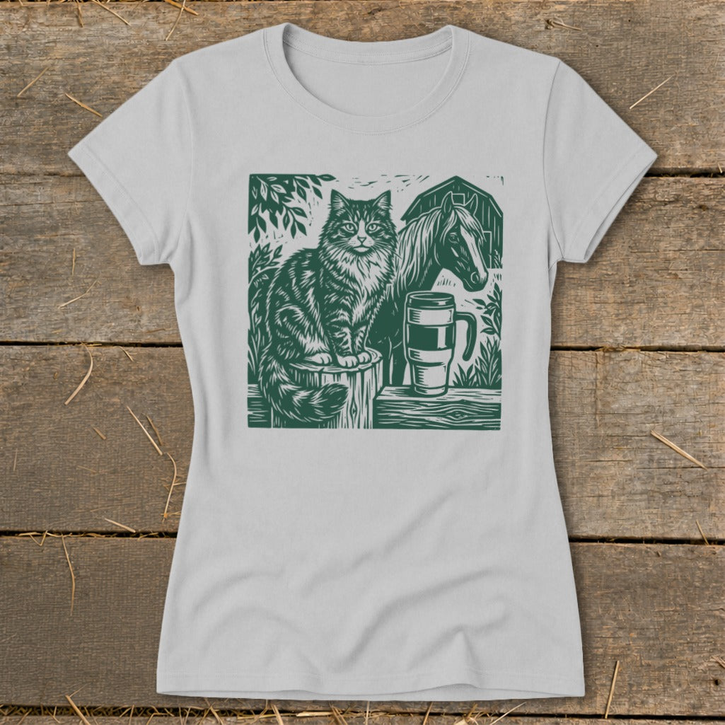 Green linocut print of a cat, horse, and mug on a light gray t-shirt.