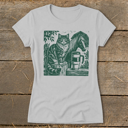 Green linocut print of a cat, horse, and mug on a light gray t-shirt.