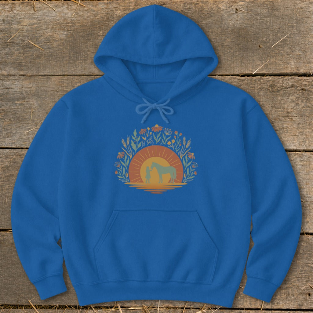 Blue hoodie with a graphic of a person and horse at sunset surrounded by flowers.
