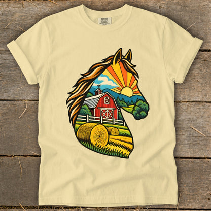 A cream-colored t-shirt with a graphic of a horse head silhouette filled with a countryside farm scene.